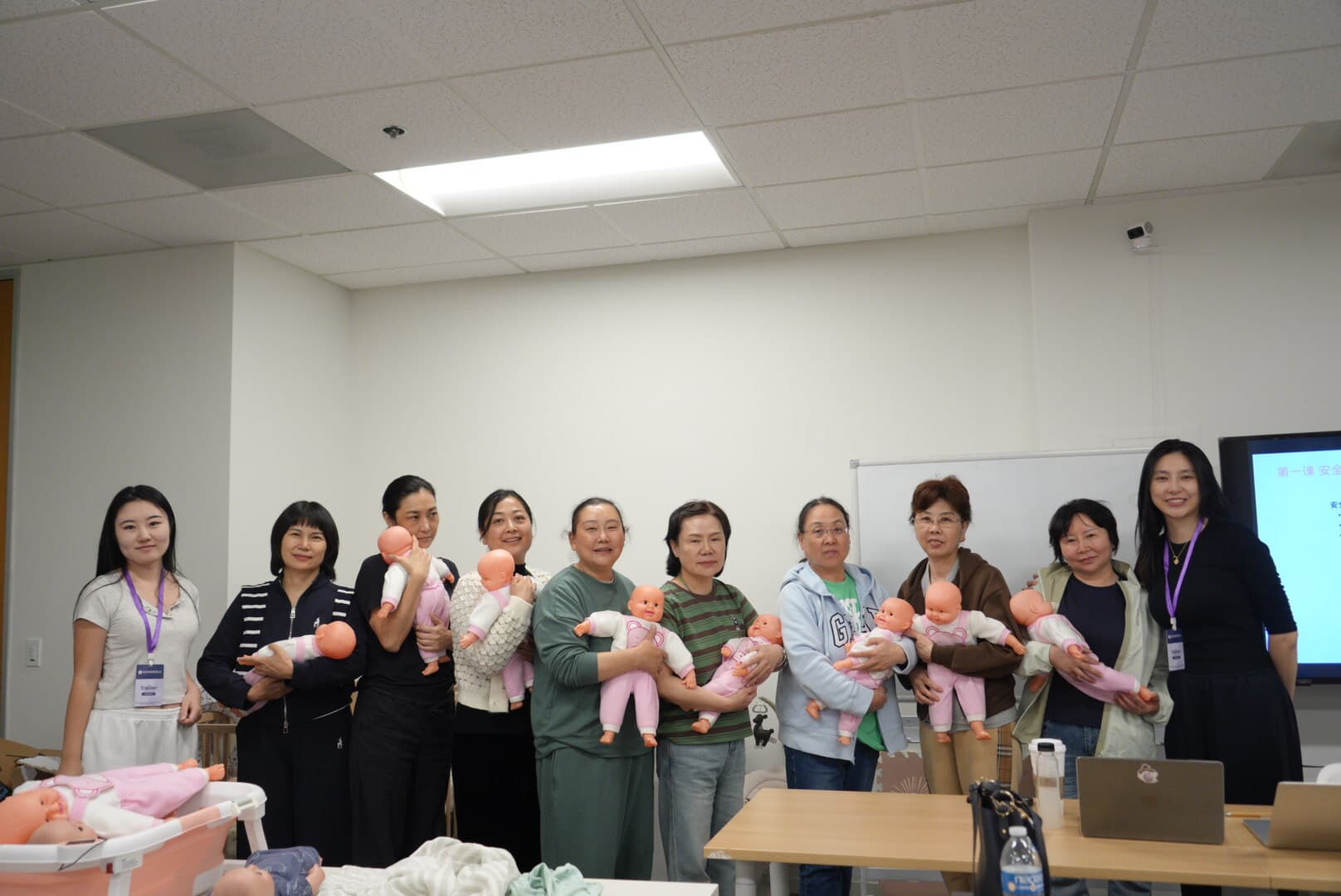 Nine doula trainees practicing newborn care with baby dolls